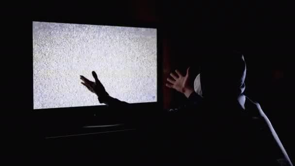 Silhouette Man i luva och medicinsk mask titta på TV-interferens med händerna upp — Stockvideo