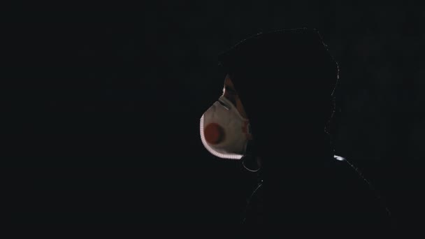 Силуэт человека в капюшоне и медицинской маске, смотрящего телевизор с фейковыми новостями. Ковид-19 — стоковое видео