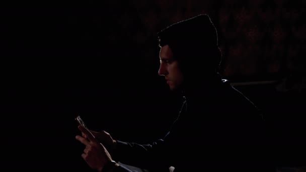 Silhouette dell'uomo nel cappuccio Scorrere Notizie Feed on Smartphone . — Video Stock