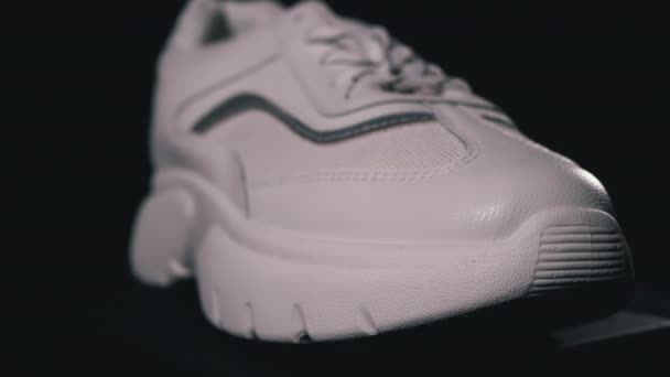 Bílá nová teniska otočí na černém pozadí. Sportovní dámské boty — Stock video