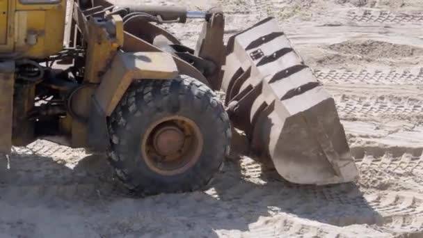 En gammal bulldozer flyttar sand med hjälp av en hink på byggarbetsplatsen — Stockvideo