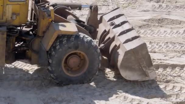 Eine alte Planierraupe bewegt Sand mit einem Eimer auf einer Baustelle