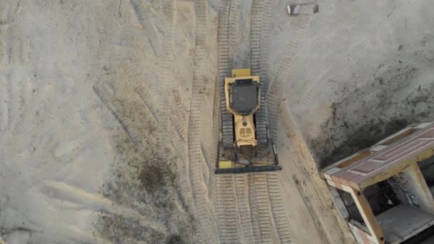Вид сверху на застрявший бульдозер на песчаной дороге на строительной площадке — стоковое видео