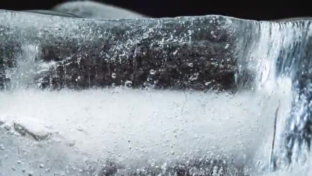 Hielo se derrite y gira sobre un fondo negro. Cronograma — Vídeos de Stock