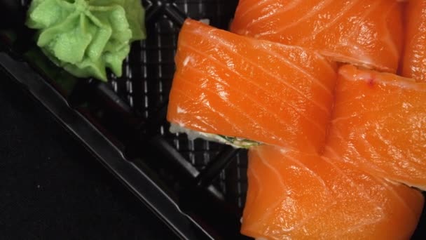 Το σούσι περιστρέφεται σε πλαστικό κουτί. Ιαπωνικό σετ ρολό σούσι Φιλαδέλφεια με σολομό — Αρχείο Βίντεο