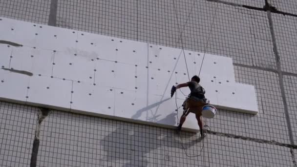 Průmyslový horolezec Izolace fasády staré high-stoupající budovy pomocí polystyrénové — Stock video