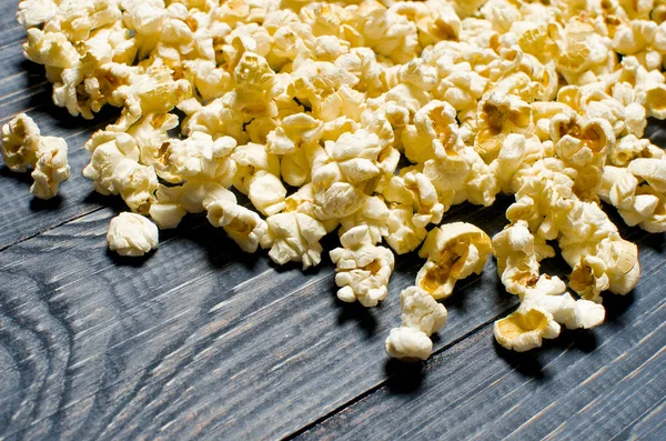 Gesalzenes Popcorn ist auf blauem Holzgrund verstreut. der Schwindel — Stockfoto