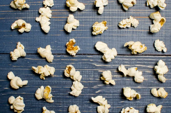 I popcorn salati sono sparsi su uno sfondo di legno blu. La Commissione ha — Foto Stock