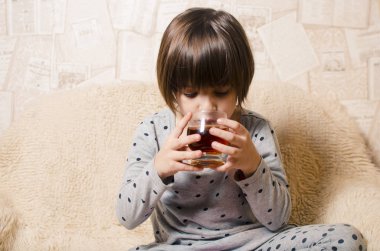 Mavi gözlü küçük bir gülümseyen kız blac ile bir bardak tutuyor