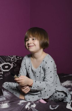 Küçük, güzel mavi gözlü kız gülümsüyor ve Tv, saatler holding