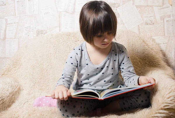 Kleines lächelndes Mädchen liest ein Buch — Stockfoto