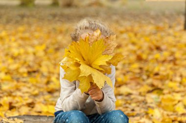 küçük kız bir buket sonbahar yaprakları.