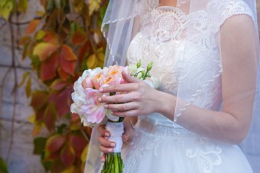 Gelin elinde bir buket düğün çiçeği tutuyor.