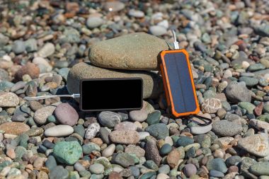 poverbank deniz kenarında çakıl taşları üzerinde yatıyor ve telefon fiyat istemek. Powerbank telefon ücretleri.