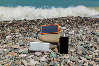 poverbank deniz kenarında çakıl taşları üzerinde yatıyor ve telefon fiyat istemek. Powerbank telefon ücretleri.