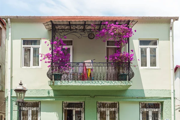 The balcony is decorated with purple flowers, a fragment of the facade of the building with beautiful purple flowers. Travel around Georgia