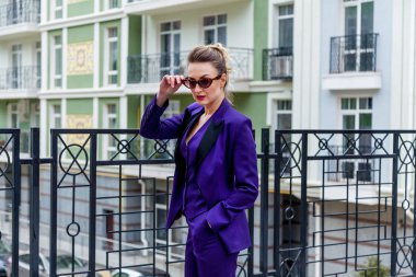 Modern binalara karşı mor takım elbiseli bir iş kadınının açık hava portresi