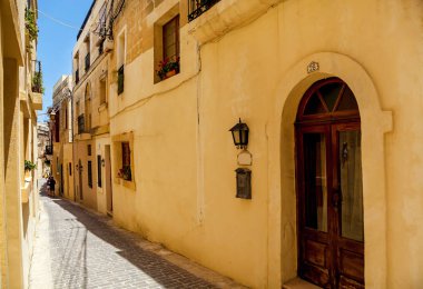 An empty narrow street with traditional Maltese architecture
