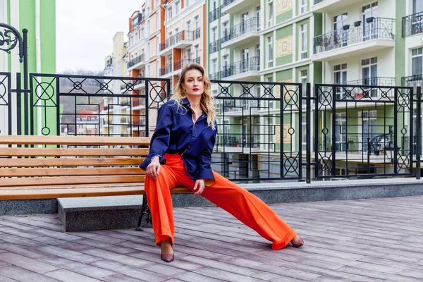 Открытый портрет привлекательной женщины в ярких брюках на фоне зданий — стоковое фото