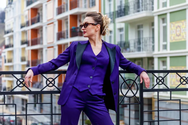 Открытый портрет деловой женщины в фиолетовом костюме против современных зданий — стоковое фото