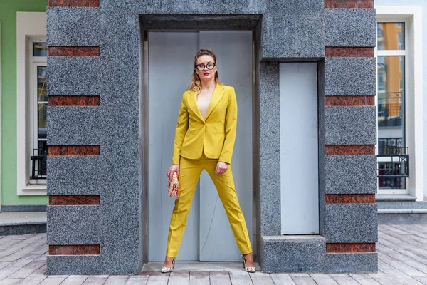 Элегантная женщина в жёлтом костюме возле лифта — стоковое фото