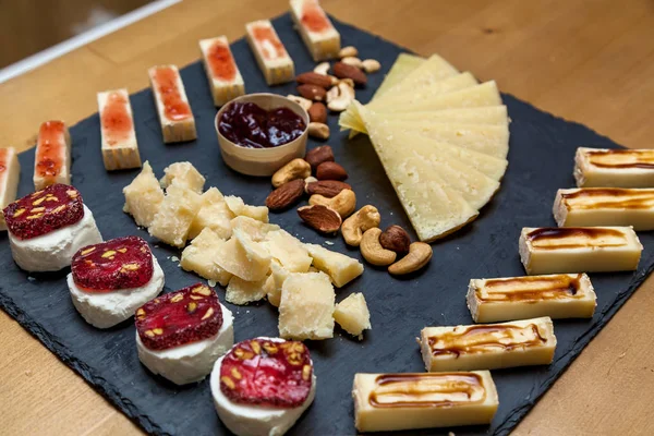 Krájení sýra z různých druhů sýrů na dřevěné desce — Stock fotografie