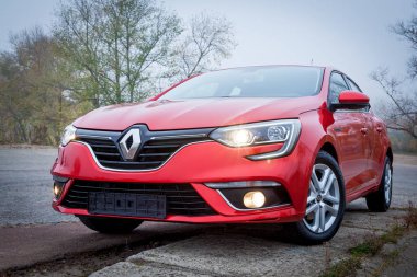 Renault Megane Sedan marka bir arabanın önden görünüşü doğa arka planında kırmızı renk