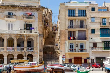 Binaların arasında merdivenleri olan bir yol iskeleye çıkıyor.