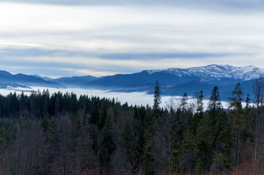 An image of white clouds over beautiful mountains