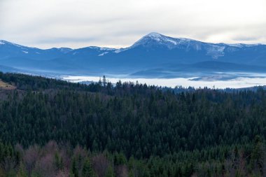 An image of white clouds over beautiful mountains
