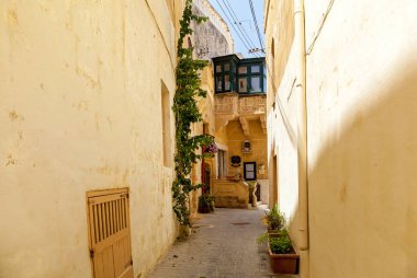 An empty narrow street with traditional Maltese architecture