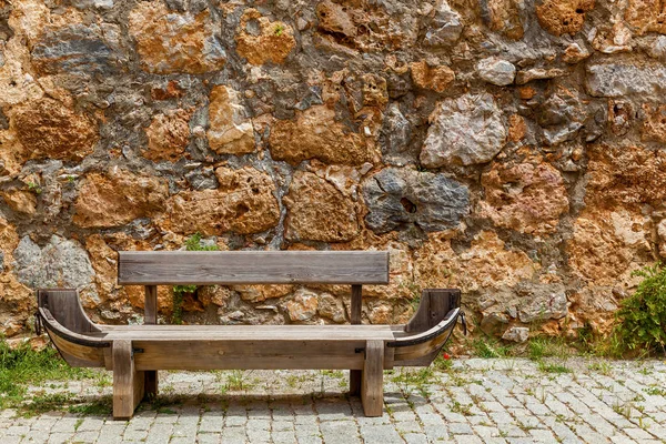 Un banco frente a un muro de piedra — Foto de Stock