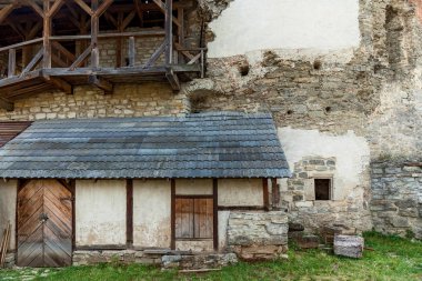 Siyah çatılı küçük bir yapı Kamianet 'teki eski bir kalenin tuğla duvarıyla korunuyor..