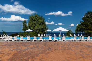 Deniz kenarında güneş pansiyonları ve şemsiyeler. Kırsal bir tatil kompleksinin dışı..