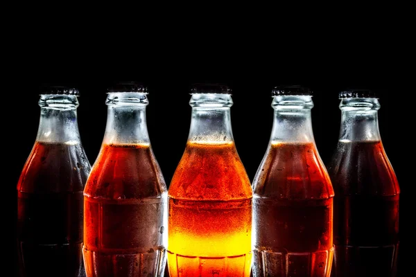 Стеклянные бутылки из-под соды, стоящие в ряд на черном фоне — стоковое фото