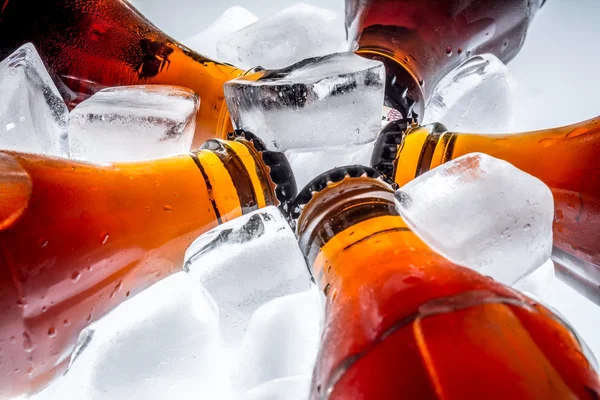 Soda glass bottles in a refrigerated ice cubes on a light background