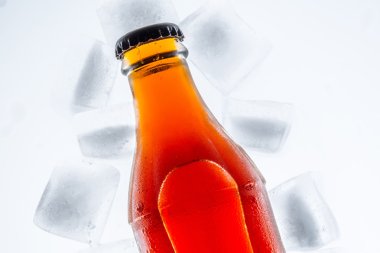 Soda cam şişede buzdolabında buz küpleri hafif bir arka plan üzerinde