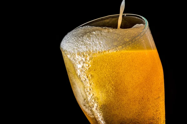 Пиво, що переповнює велике скло з піною та бульбашками, ізольоване на чорному тлі — стокове фото
