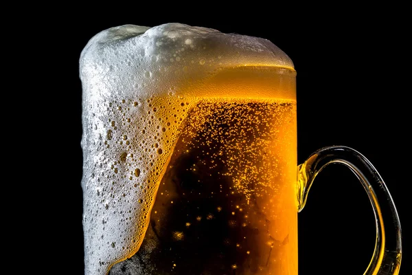 Пиво, що переповнює велике скло з піною та бульбашками, ізольоване на чорному тлі — стокове фото