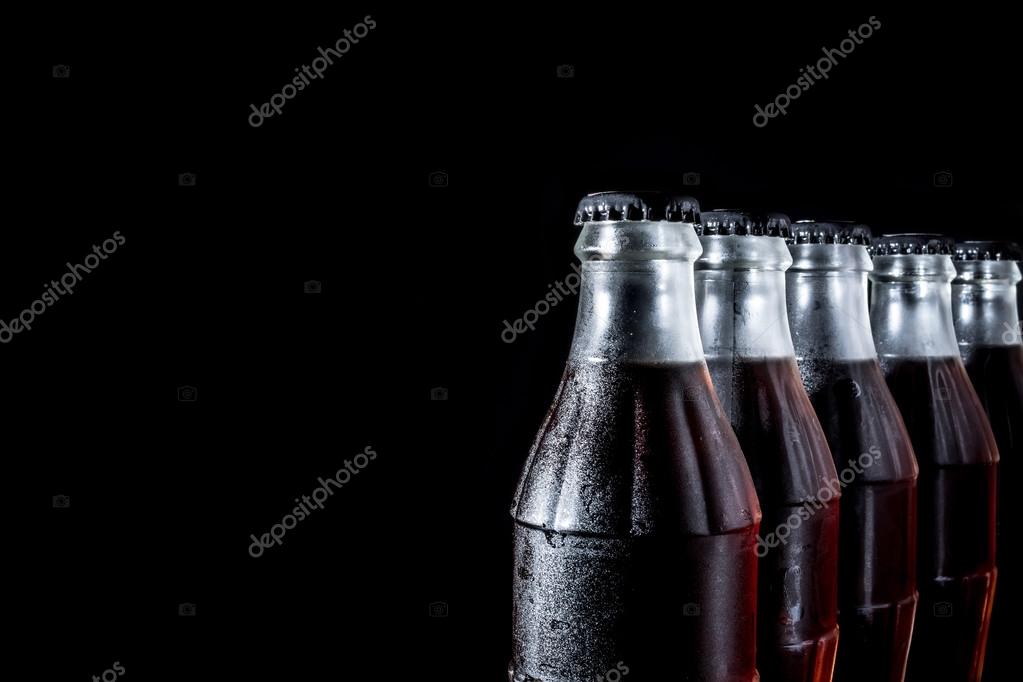 Soda glass bottles standing in a row isolated on a black background