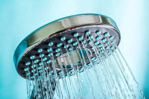 Moderne heiße Dusche mit Wasserstrahl aus nächster Nähe auf blauem Hintergrund — Stockfoto