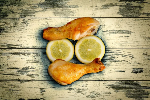 Chicken legs with sliced lemon on wooden vintage background boards. Old grunge style.
