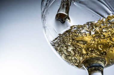 Beyaz şarap bir bardak dökme, gri arka plan üzerinde beyaz şarap sıçrama akışı