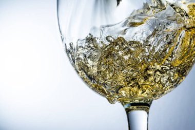 Beyaz şarap bir bardak dökme, gri arka plan üzerinde beyaz şarap sıçrama akışı