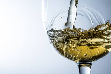 Beyaz şarap bir bardak dökme, gri arka plan üzerinde beyaz şarap sıçrama akışı