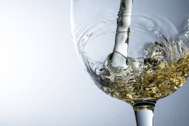 Beyaz şarap bir bardak dökme, gri arka plan üzerinde beyaz şarap sıçrama akışı