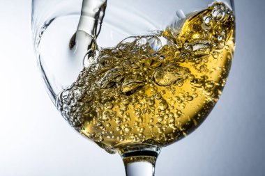 Beyaz şarap bir bardak dökme, gri arka plan üzerinde beyaz şarap sıçrama akışı