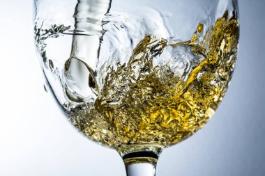 Beyaz şarap bir bardak dökme, gri arka plan üzerinde beyaz şarap sıçrama akışı