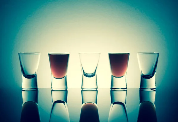 Kleine Gläser mit einem Getränk, das auf einem Tisch Alkoholflecken aufweist. alter Retro-Vintage-Stil. — Stockfoto