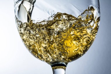 Gri arka plan, beyaz şarap bir bardak dökülen dere üzerinde beyaz şarap sıçrama.